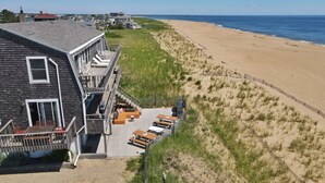 Een strandhuis met een houten terras, zitplaatsen buiten en uitzicht op zee.
