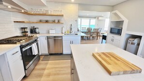 Une cuisine moderne avec des meubles blancs, un plan de travail en bois et une vue sur la salle à manger.
