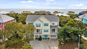 A two-story house with a balcony, surrounded by trees and a view of the ocean. - Duplex with private pool and easy beach access,in the Spinnaker's Reach (Emerald Isle)