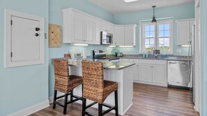 A kitchen with white cabinets, a microwave, a sink, and a window. - Duplex with private pool and easy beach access,in the Spinnaker's Reach (Emerald Isle)