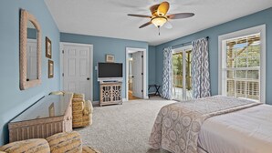 A bedroom with a bed, a television, a ceiling fan, and a view of the outdoors through a door. - Duplex with private pool and easy beach access,in the Spinnaker's Reach (Emerald Isle)