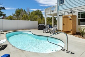 A swimming pool with a metal ladder, lounge chairs, and a wooden deck area.