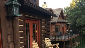 Una terraza de madera con dos mecedoras y una valla de madera.