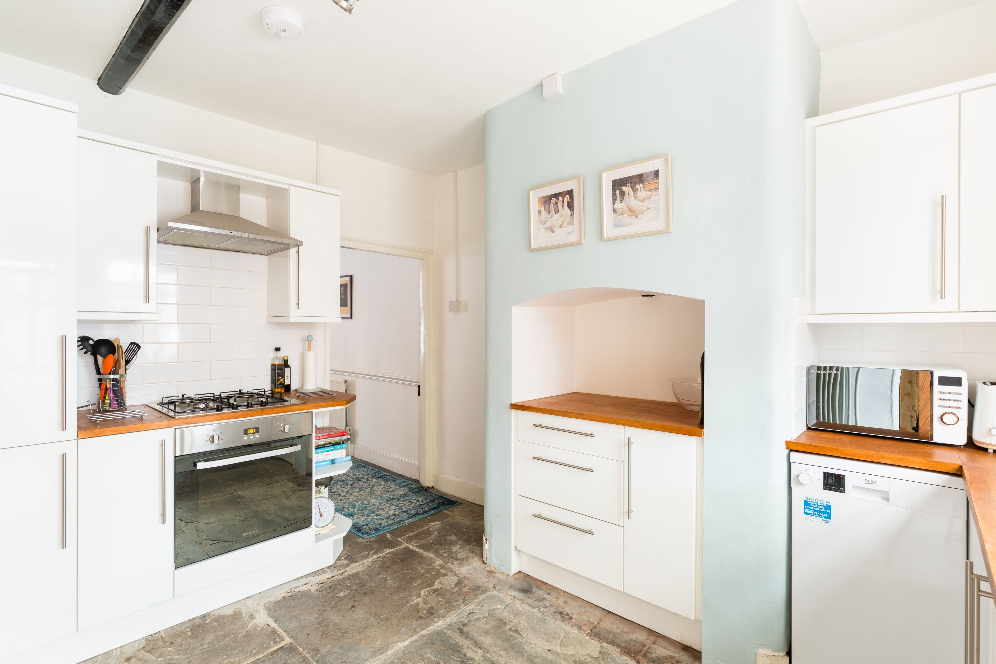 A compact kitchen with white cabinets, a gas stove, an oven, a dishwasher, and a microwave.