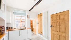 A kitchen with white cabinets, a wooden countertop, and a window with a blue blind. - Shakespeare House, Free Parking, Town Centre Location (Stratford-upon-Avon)