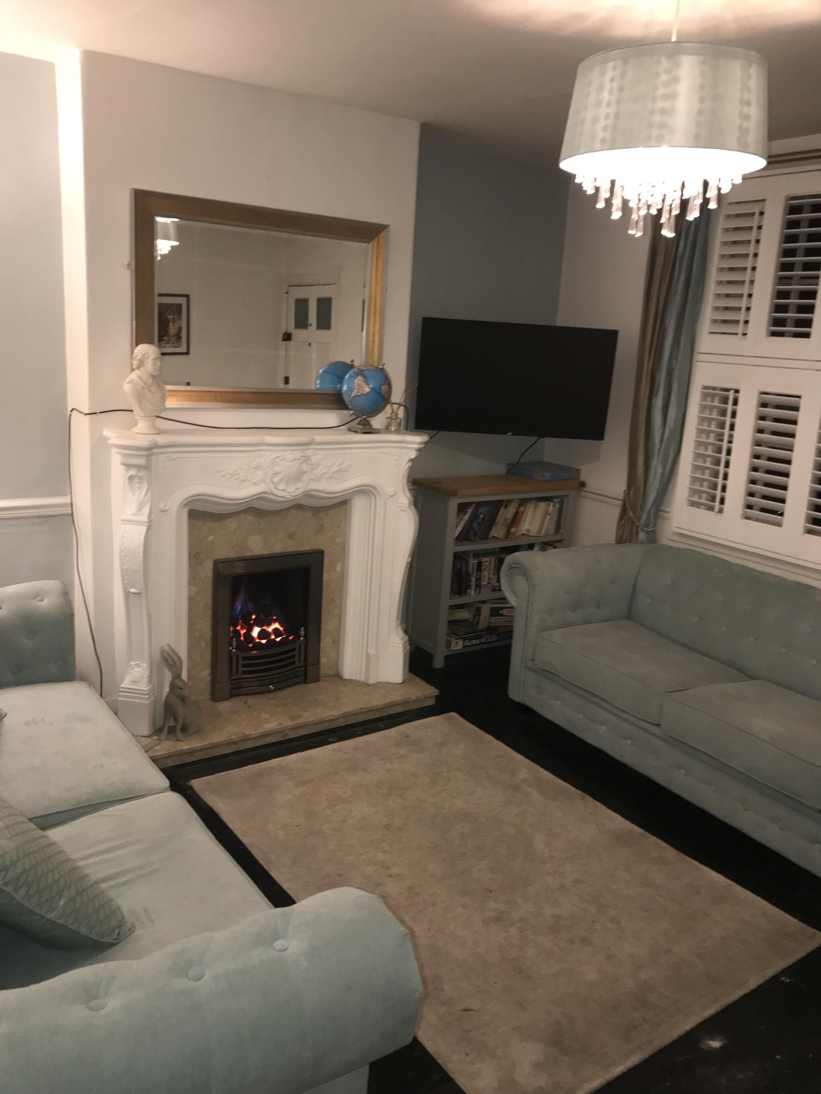 A living room with a fireplace, a television, and a light blue sofa.