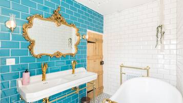 A bathroom with a white sink, gold fixtures, a large mirror, and blue-tiled walls.