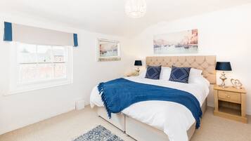 A bedroom with a bed, bedside tables, a chandelier, and artwork on the walls.