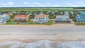 Un quartier résidentiel situé sur la côte, avec des maisons donnant sur la plage, une plage de sable et une vue dégagée sur l’océan.