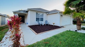 A residential house with a front yard, a patio with chairs, and a palm tree. - 4 Bedroom South Facing Pool Gem! (Haines)