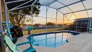 A covered outdoor pool area with a view of a residential neighborhood during sunset. - 4 Bedroom South Facing Pool Gem! (Haines)