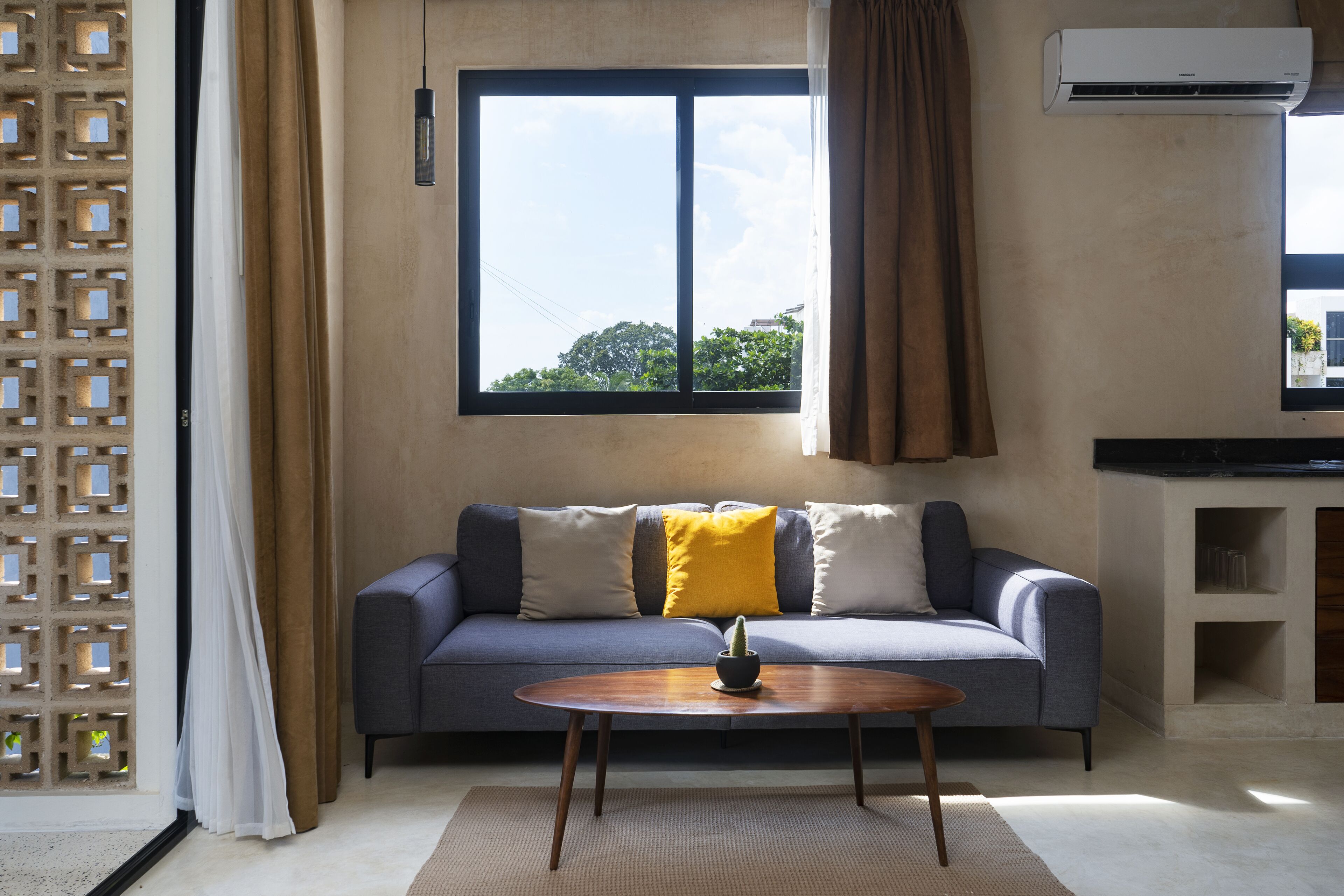 A living room with a sofa, a coffee table, and a window with a view of trees.