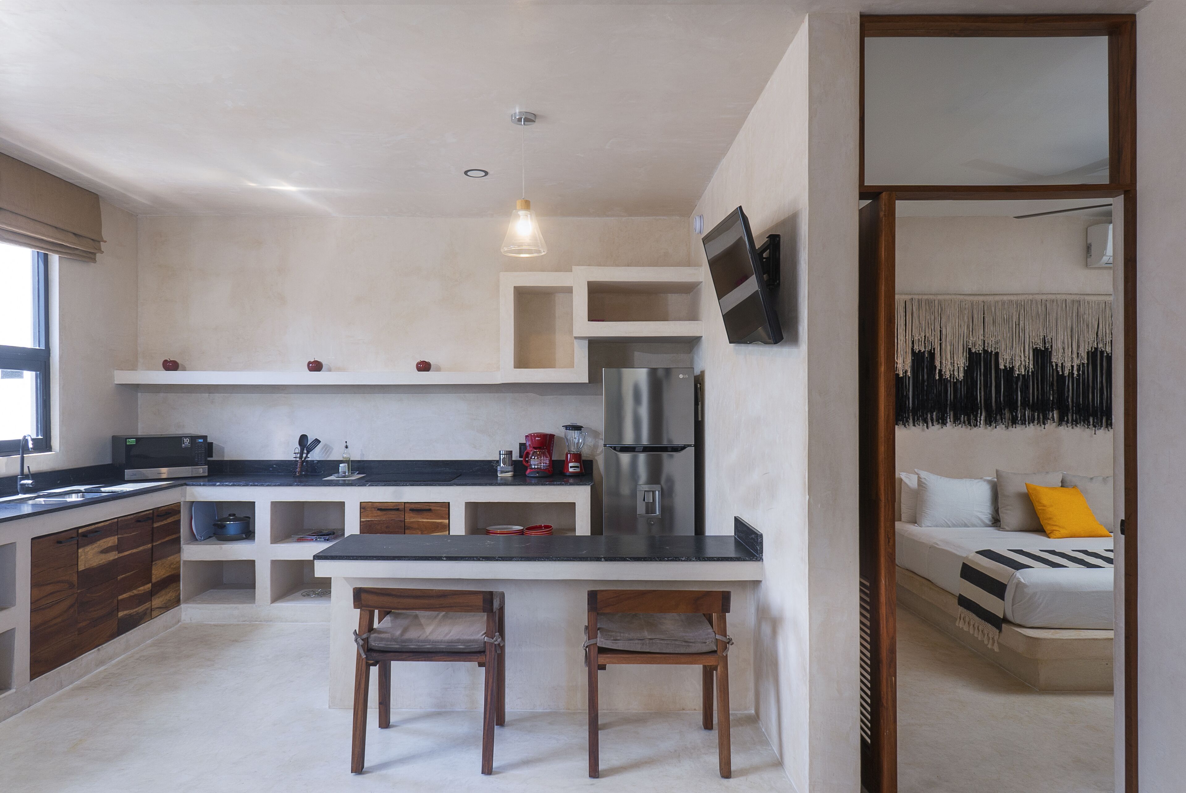 A modern kitchen with a built-in microwave, refrigerator, and a dining area with two chairs.