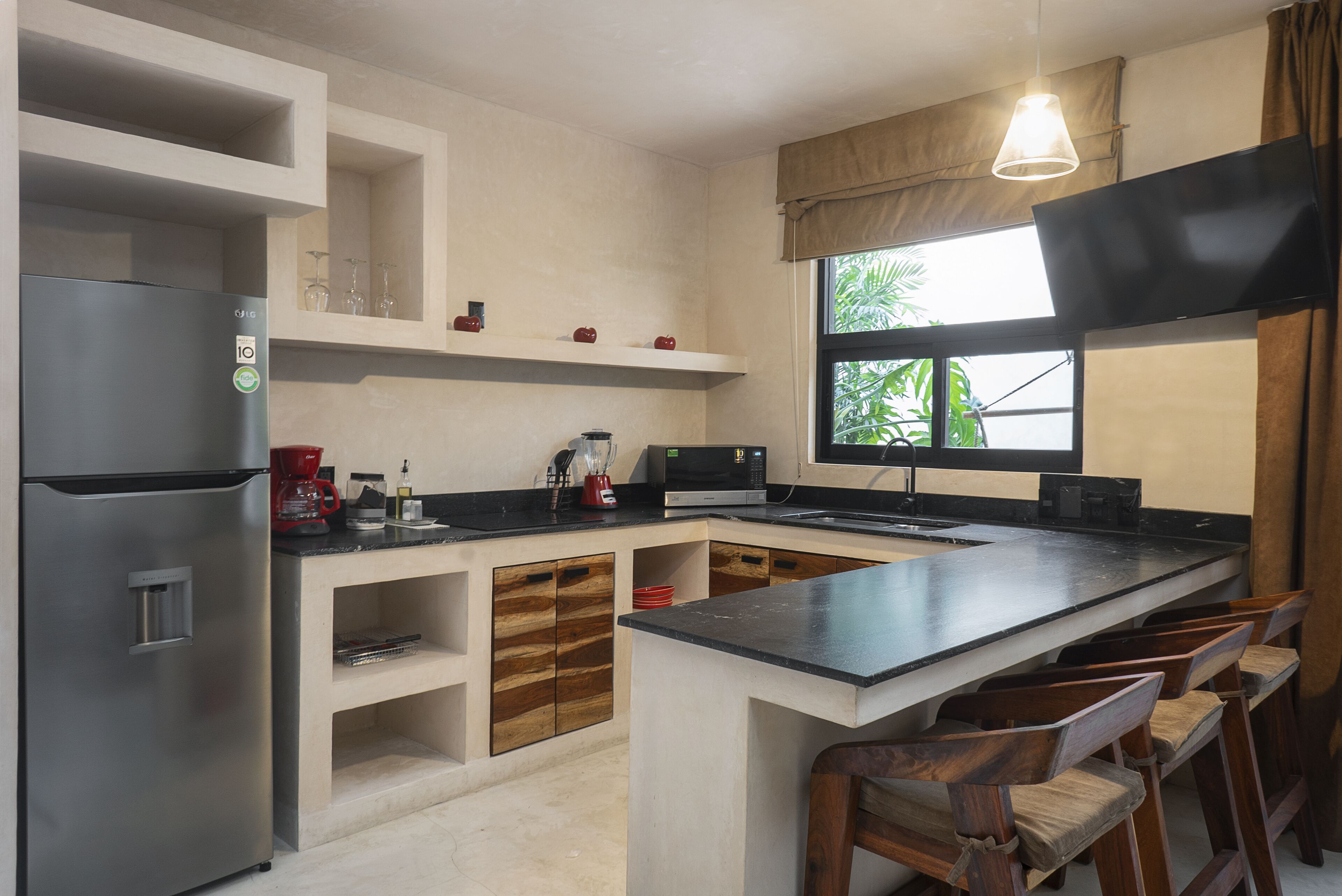 A modern kitchen with a built-in island, stainless steel appliances, and wooden bar stools.