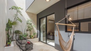 A modern outdoor space with a hammock, a black wire chair, and various potted plants. - UJO Tulum (Tulum)