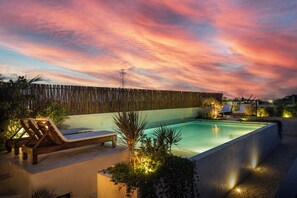 Une piscine avec des chaises longues et une clôture en bois en arrière-plan.