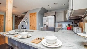 Una cucina moderna con piano di lavoro in marmo, elettrodomestici in acciaio inossidabile e dettagli in legno.