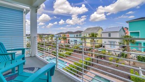 A balcony with turquoise chairs, a pool, and a view of colorful houses and mountains. - 2914 Salted Rim Road (Kissimmee)