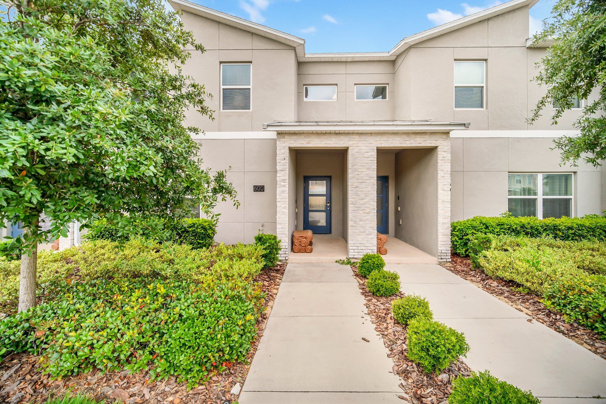 A modern two-story house with a front entrance, a driveway, and well-maintained landscaping.