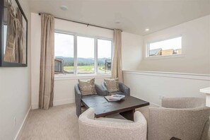 Ein Zimmer mit einer Sofagarnitur, einem Couchtisch und einem Fenster mit Landschaftsblick.