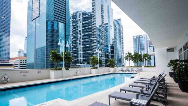 A rooftop pool with lounge chairs and a view of high-rise buildings. - TC-2607 · Bright and cozy 2 bedroom free parking at brickell (Miami)
