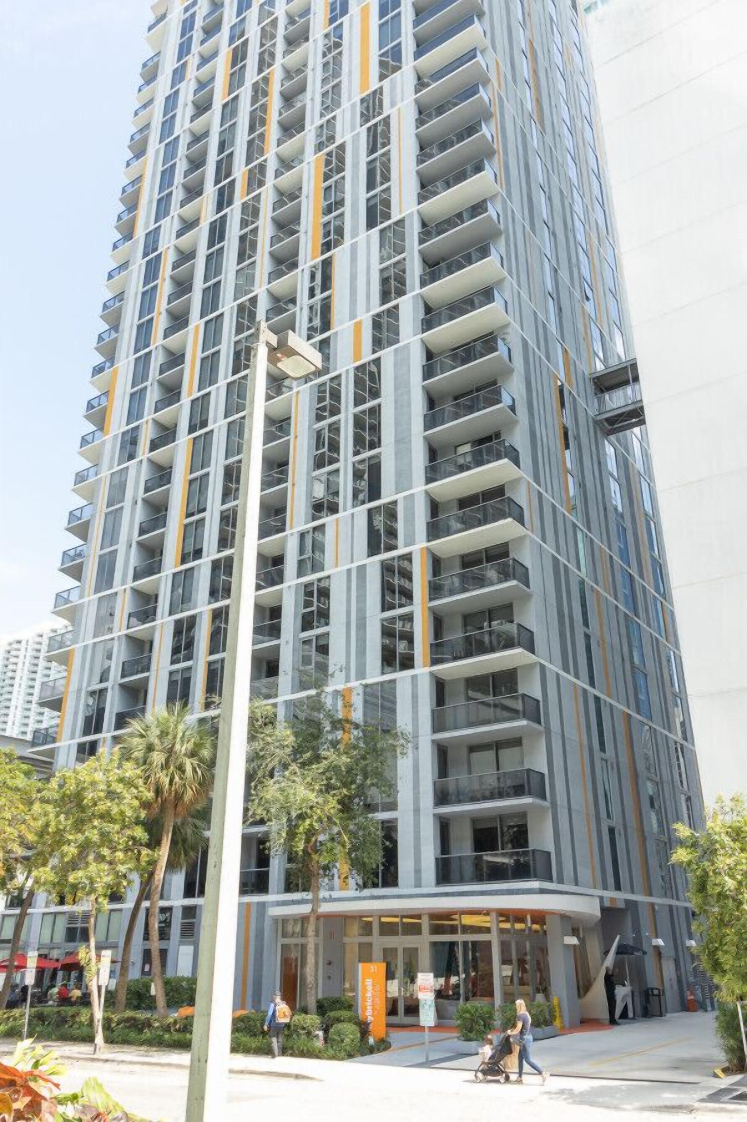 A tall, modern building with multiple balconies and a curved entrance.