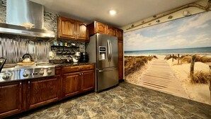 A kitchen with wooden cabinets, a stainless steel refrigerator, and a stone backsplash.