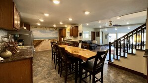 A spacious kitchen with a central island, wooden cabinets, and a stone floor.