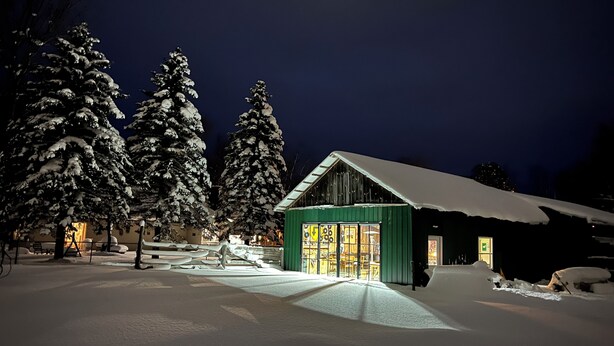 A snow-covered landscape with a cabin featuring large windows and a green exterior.