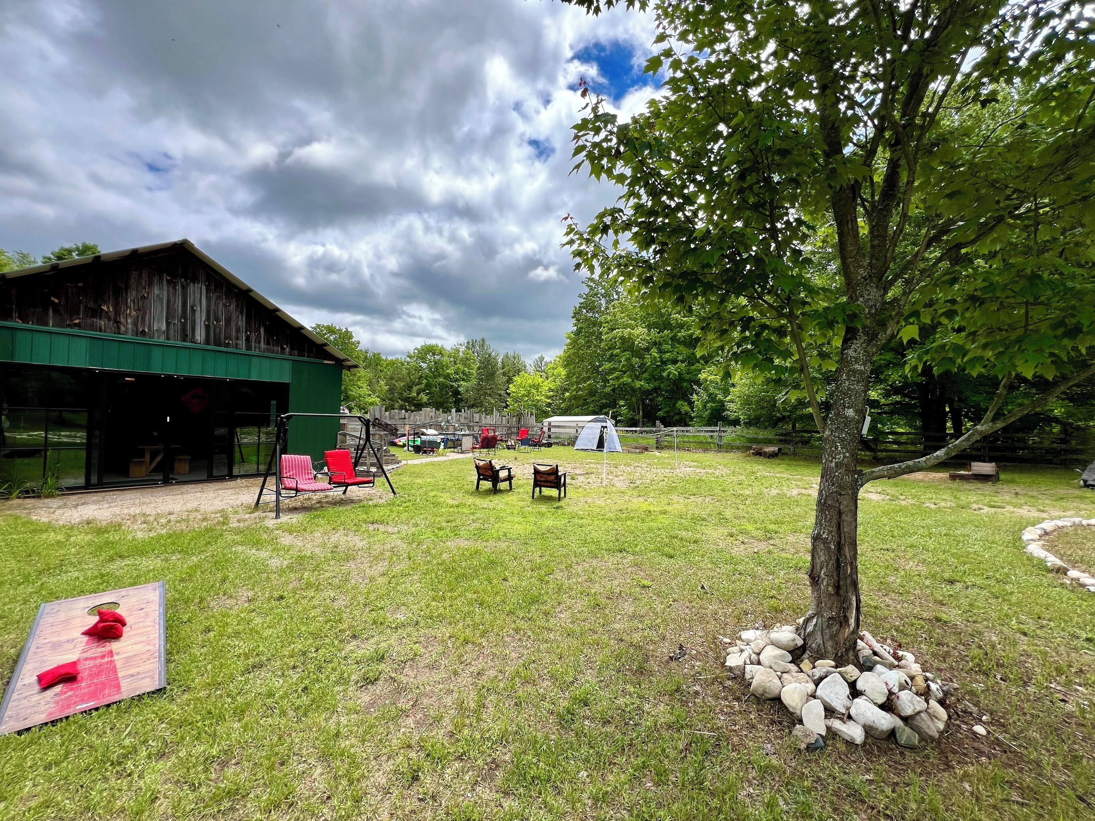 A rustic outdoor area with a wooden barn, a tent, and a swing set.