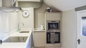 A compact kitchen with a sink, stove, oven, and a clock on the wall. - 1 bedroom accommodation in Dronfield (Dronfield)