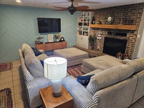 A living room with a sofa set, a coffee table, a TV, a fireplace, and a bookshelf.