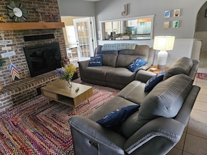 A living room with a fireplace, a sofa, a coffee table, and a colorful rug.