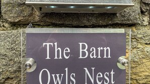 A sign reading "The Barn Owls Nest" mounted on a stone wall.