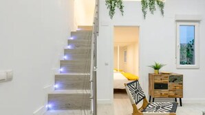 A modern interior with a staircase, a bed, a wooden chair, and a small cabinet. - Your home in the center of Madrid (Madrid)