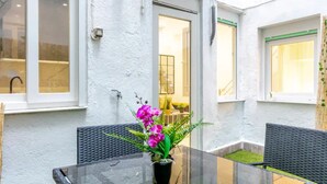 A glass table with two chairs and a potted plant with pink flowers. - Your home in the center of Madrid (Madrid)