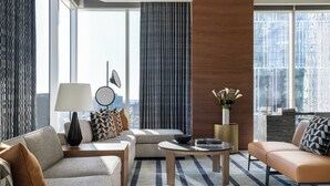 Ein modernes Wohnzimmer mit Sofa, Sessel, Couchtisch und einem großen Fenster mit Blick auf die Stadt.