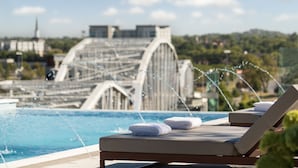 Zona junto a la piscina con sillones de descanso y una fuente de agua.