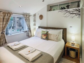 A neatly made bed with pillows, a bedside lamp, and a window with curtains.