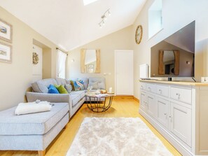 A modern living room with a grey sofa, white cabinets, and a large mirror.