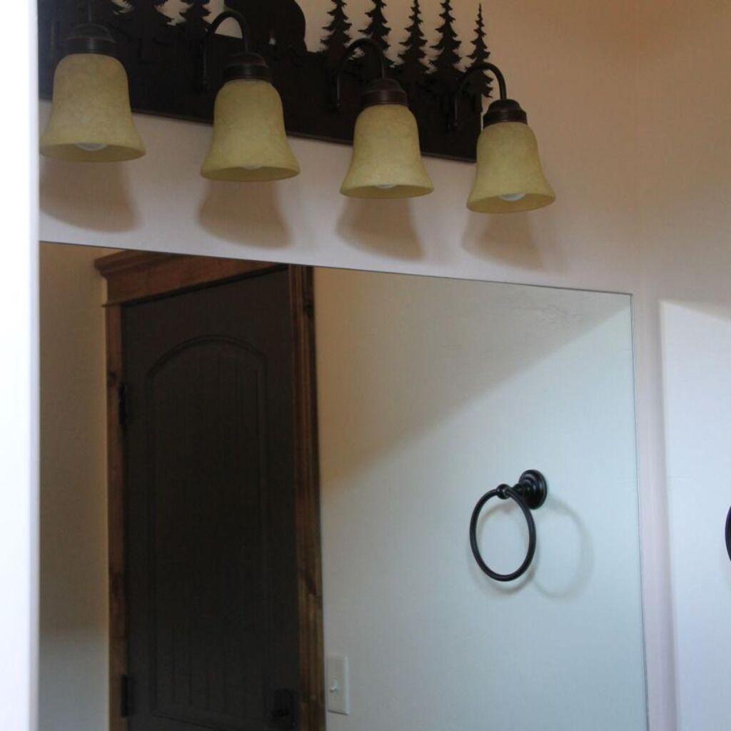 Un pasillo con una puerta de madera, un aplique de pared con cuatro lámparas y un timbre.