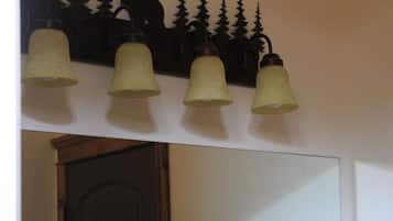 Un pasillo con una puerta de madera, un aplique de pared con cuatro lámparas y un timbre.