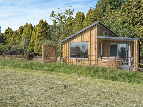 A wooden cabin with large windows, a balcony, and a view of a forested area. - The Tranquil Orchard - Nuthatch-UK32791 (Brocklehirst, near Dumfries)