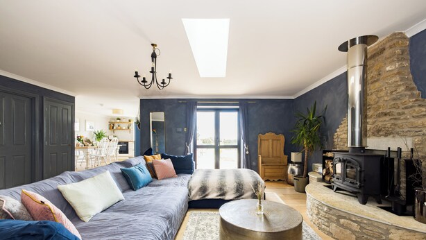 Una sala de estar moderna con un sofá, una mesa redonda de centro, una chimenea de piedra y un ventanal grande.