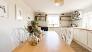 Una cocina con armarios blancos, una mesa de comedor de madera y varios electrodomésticos.