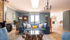 Un salon avec un canapé bleu, une table basse en verre et une cheminée en pierre.