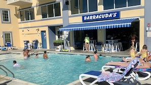 A pool area with lounge chairs and a building labeled 'BARRACUDA'S' in the background. - Available Country Calling! Linens and parking. Short walk to Beach and Boards. (Ocean City)