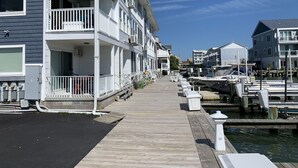 A waterfront property with a wooden dock, multiple balconies, and a marina with boats. - Available Country Calling! Linens and parking. Short walk to Beach and Boards. (Ocean City)