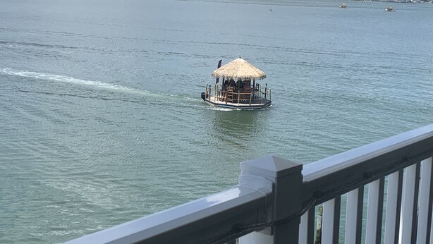 A boat with a thatched roof and seating, floating on calm water. - Available Country Calling! Linens and parking. Short walk to Beach and Boards. (Ocean City)