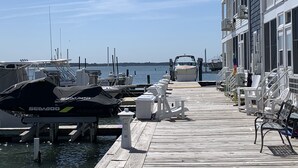 A marina with boats docked, a wooden pier, and a building with balconies. - Available Country Calling! Linens and parking. Short walk to Beach and Boards. (Ocean City)